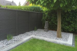 Betonzaun mit Ziegelsteinen in Gartenlandschaft